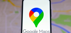 Nahaufnahme eines Smartphones, auf dem das Google-Maps-Logo zu sehen ist, mit einer Karte, wie man sie in Google Maps sehen würde, im Hintergrund.