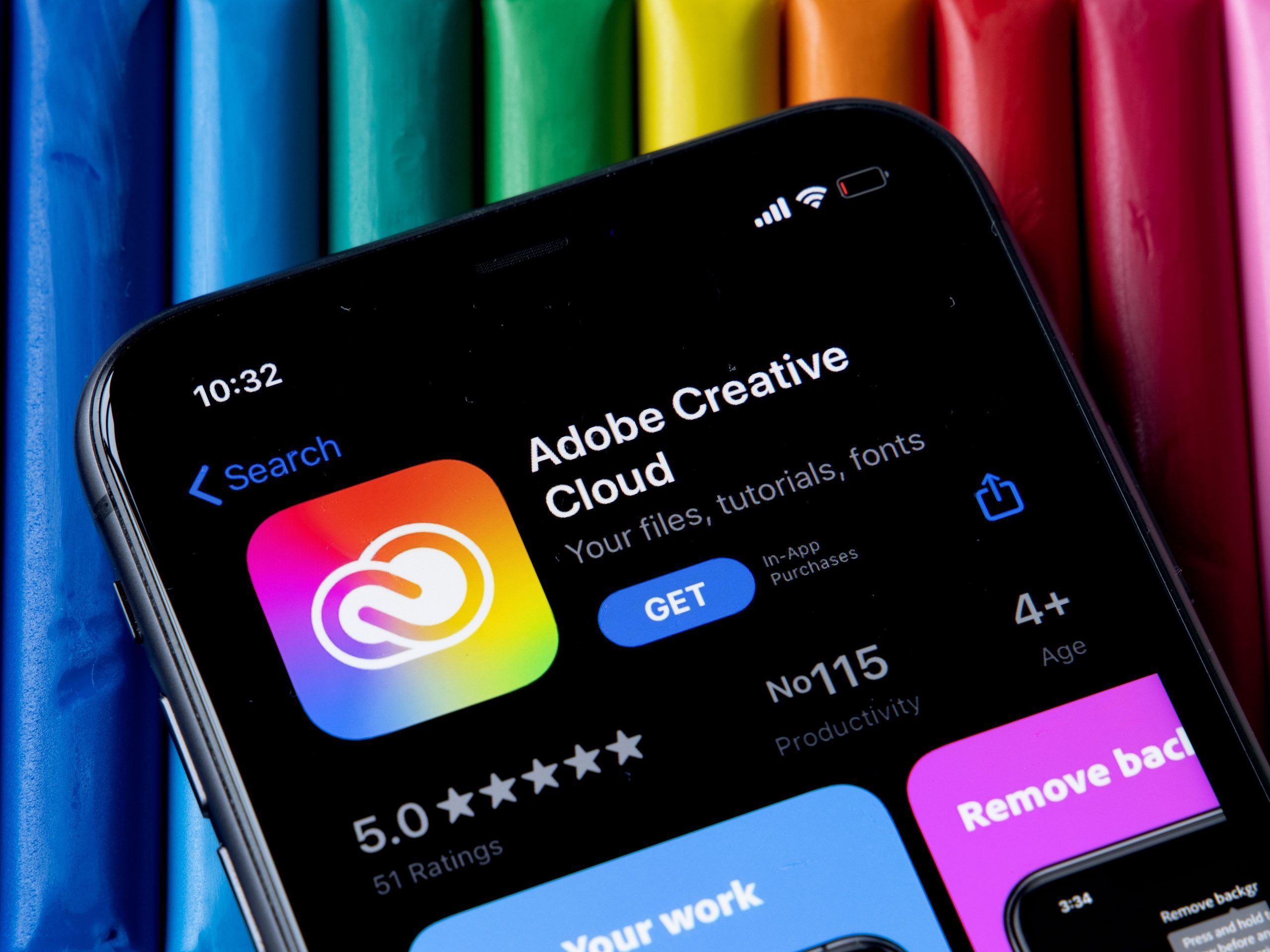 Nahaufnahme eines Smartphone-Bildschirms, der die Adobe Creative Cloud-App-Seite im App Store anzeigt, mit bunten Markierungen im Hintergrund. Das App-Symbol ist zusammen mit der Schaltfläche 