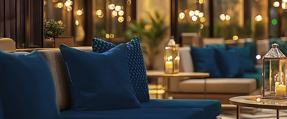 Das bild zeigt eine Hotellounge links mit einer Sitruppe grünen Sitzpolstern und rechts mit einer Tischlaterne, inder eine Kerze brennt